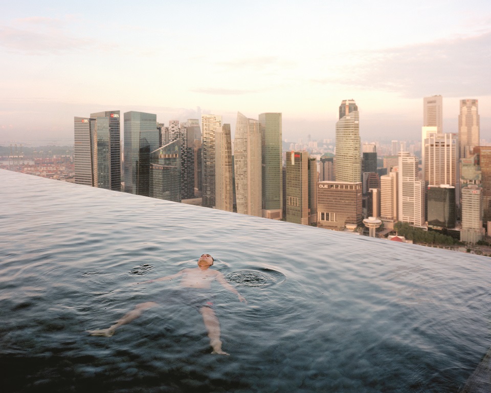 A man floats in the 57th-floor swimming pool of the Marina Bay Sands Hotel, with the skyline of Central,Σ the Singapore financial district, behind him. Singapore
